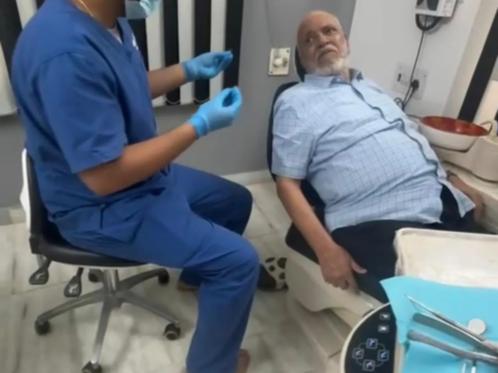 A dentist at the clinic talking a patient through what he has found.
